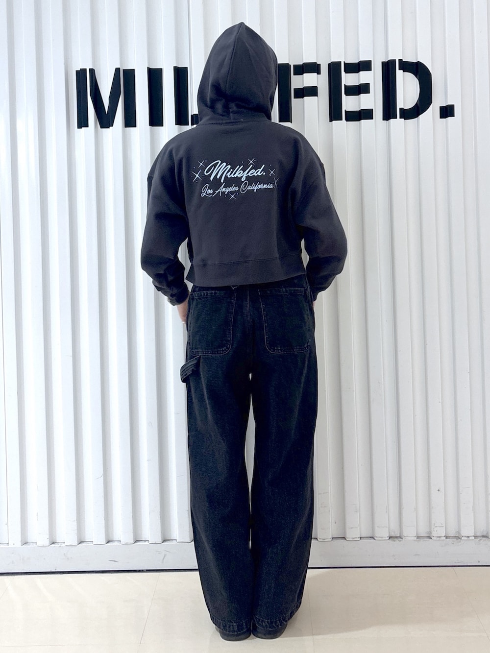 グレー系のパーカー、ブラック系のデニムパンツ、ブラック系のショルダーバッグを着用したレディースの冬コーディネートの6枚目の写真