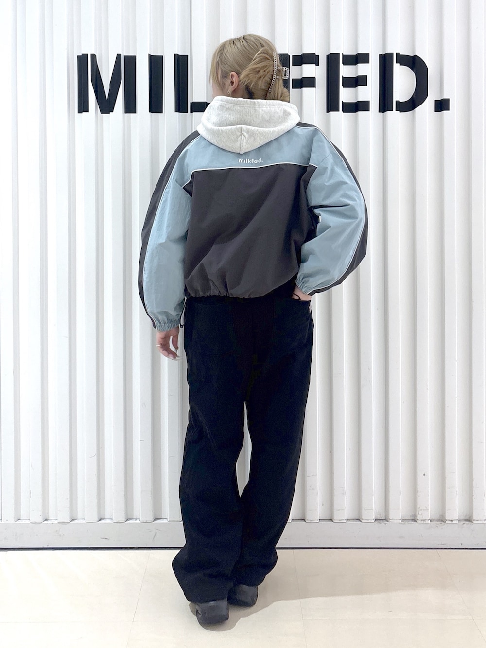 グレー系のナイロンジャケット、ベージュ系のパーカー、ブラック系のスウェットパンツを着用したレディースの春コーディネートの5枚目の写真