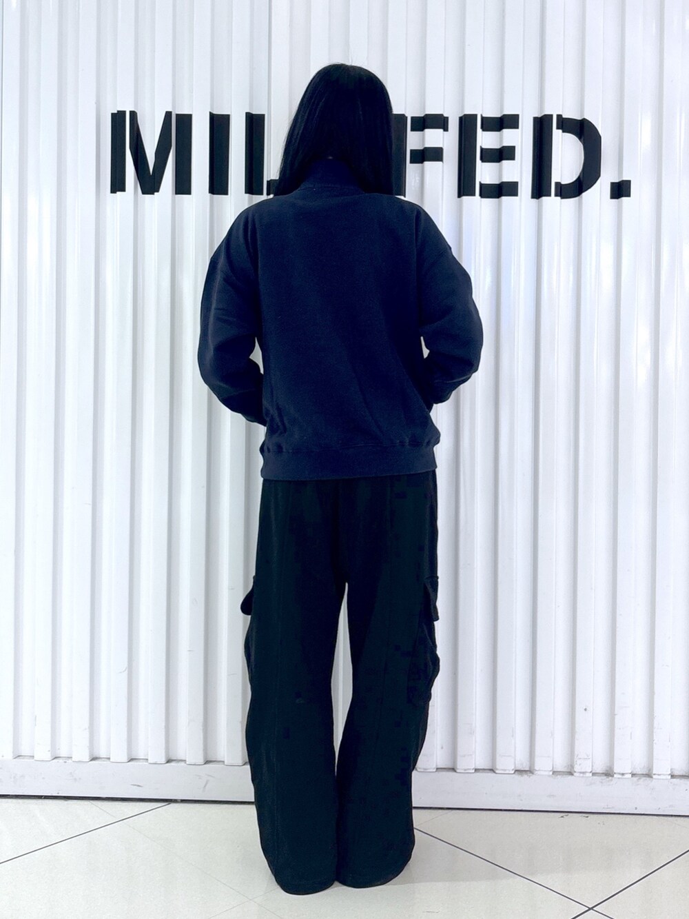 ブルー系のスウェット、ブラック系のスウェットパンツ、ブラック系のTシャツ/カットソーを着用したレディースの秋コーディネートの2枚目の写真