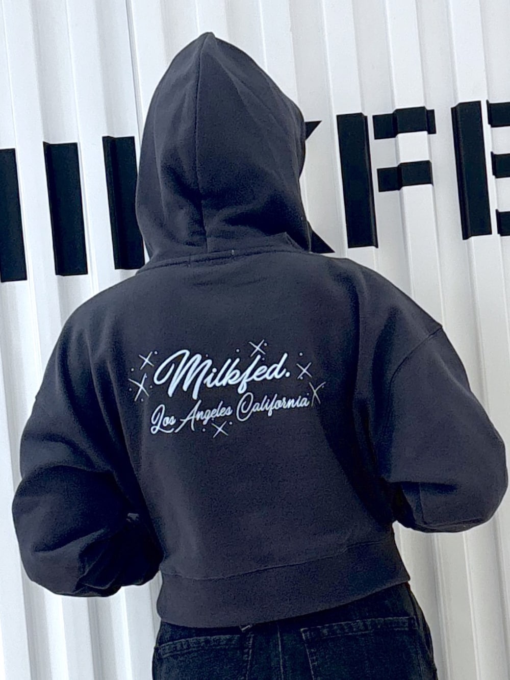 グレー系のパーカー、ブラック系のデニムパンツ、ブラック系のショルダーバッグを着用したレディースの冬コーディネートの7枚目の写真