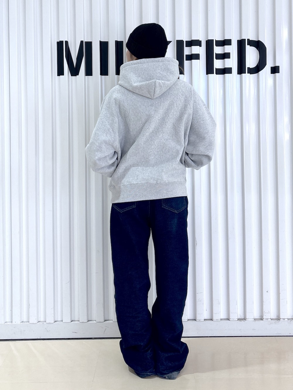 ブラック系のブルゾン、ブルー系のデニムパンツ、グレー系のパーカーを着用したレディースの冬コーディネートの6枚目の写真