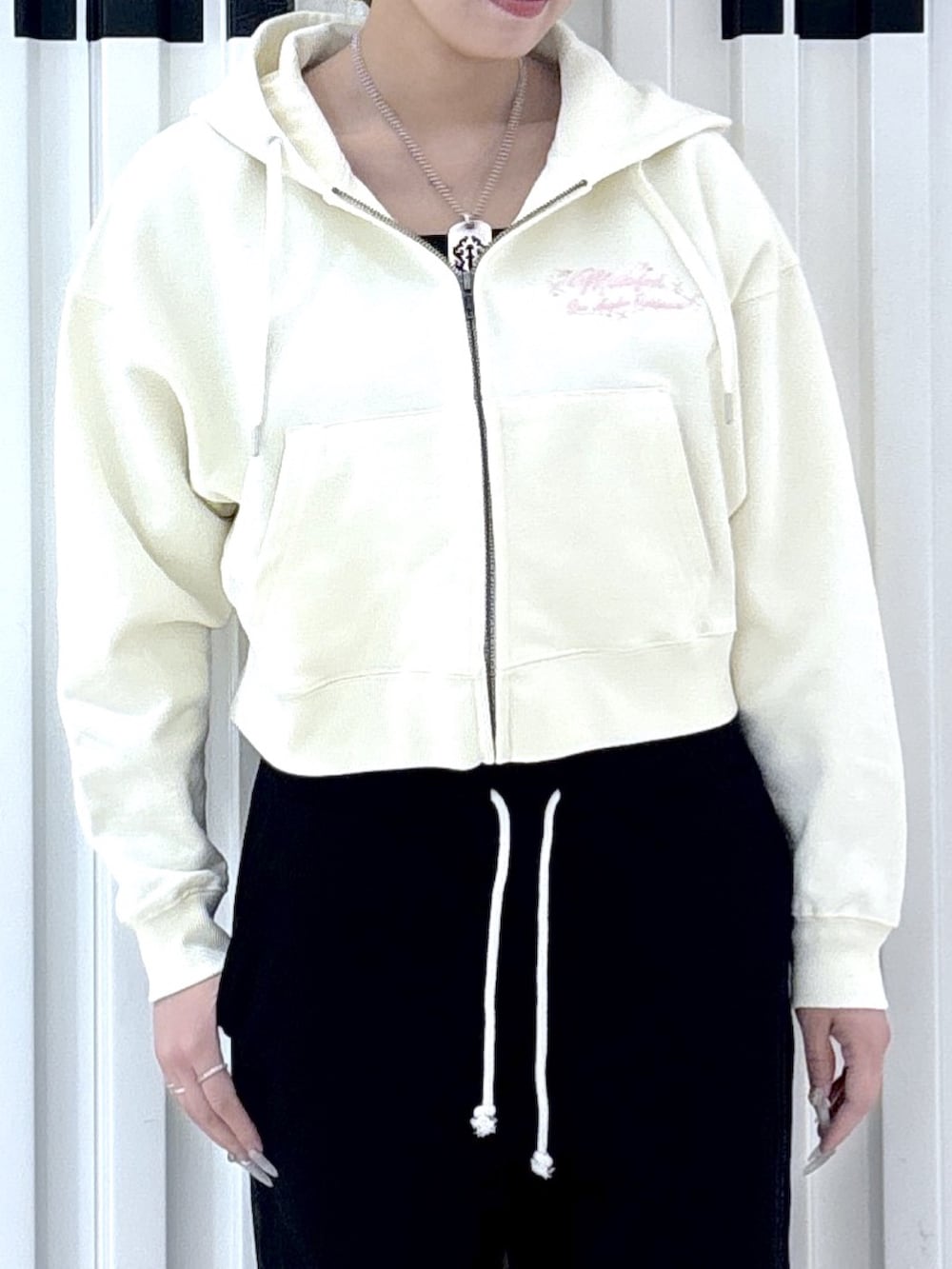 ホワイト系のパーカー、ブラック系のスウェットパンツを着用したレディースの春コーディネートの3枚目の写真