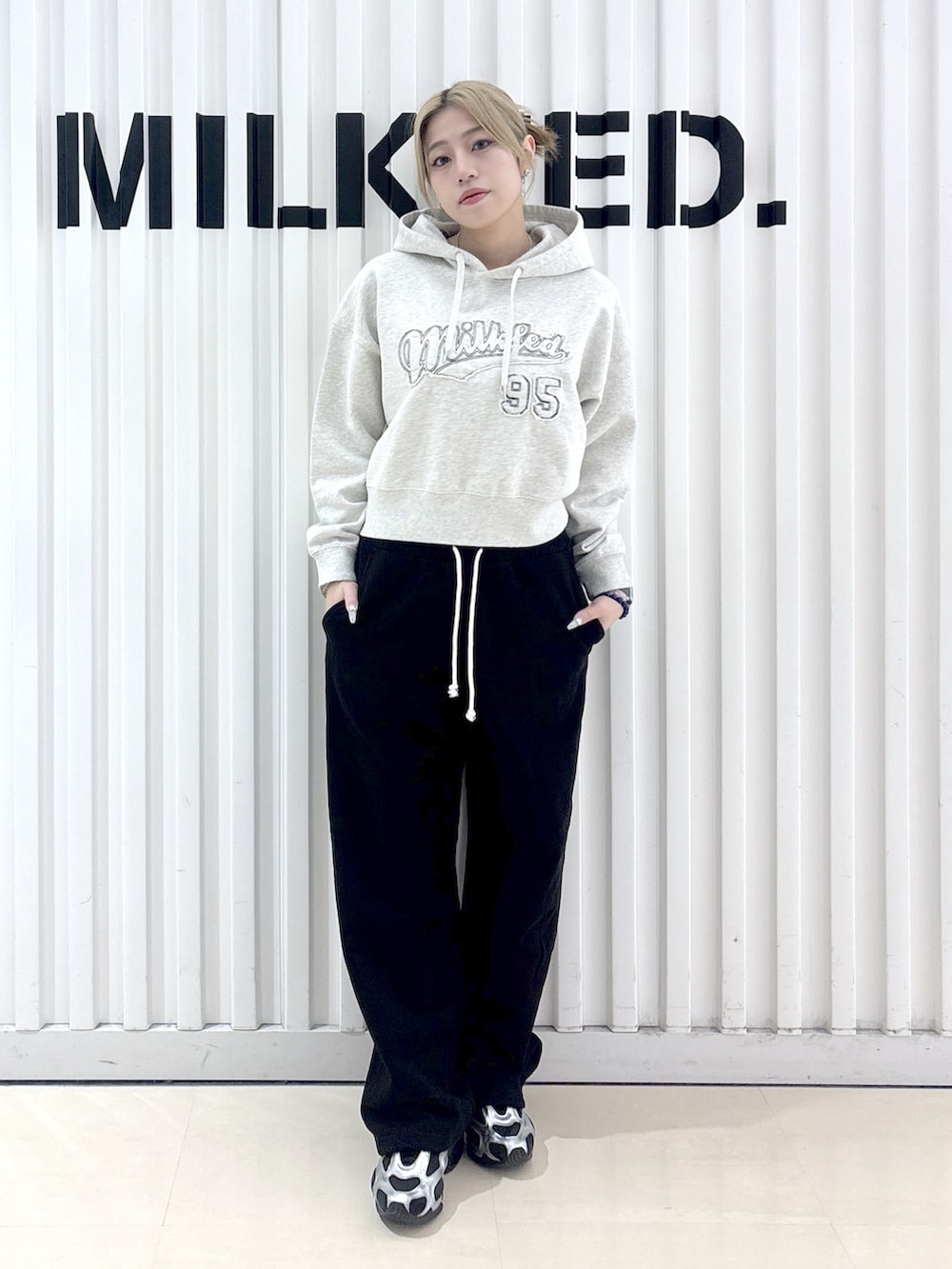 グレー系のナイロンジャケット、ベージュ系のパーカー、ブラック系のスウェットパンツを着用したレディースの春コーディネートの9枚目の写真