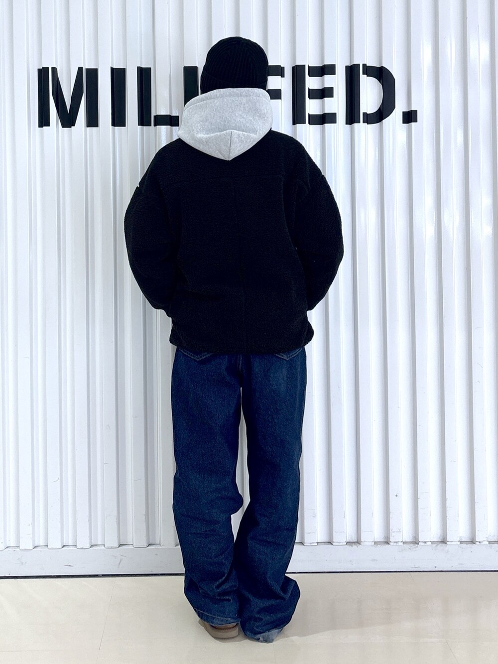 ブラック系のブルゾン、ブルー系のデニムパンツ、グレー系のパーカーを着用したレディースの冬コーディネートの2枚目の写真