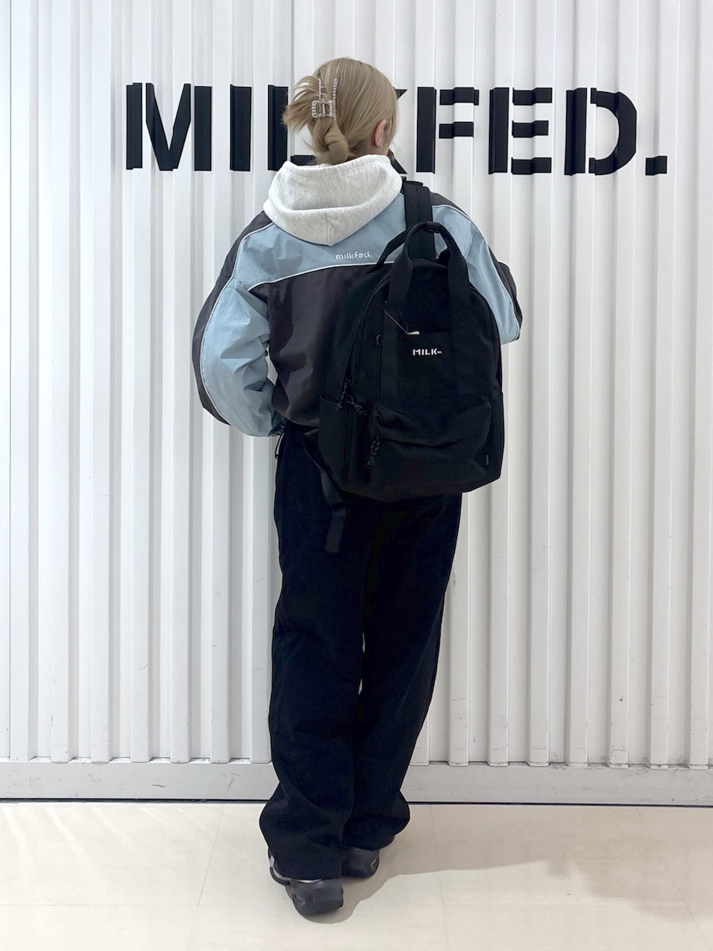 グレー系のナイロンジャケット、ベージュ系のパーカー、ブラック系のスウェットパンツを着用したレディースの春コーディネートの2枚目の写真