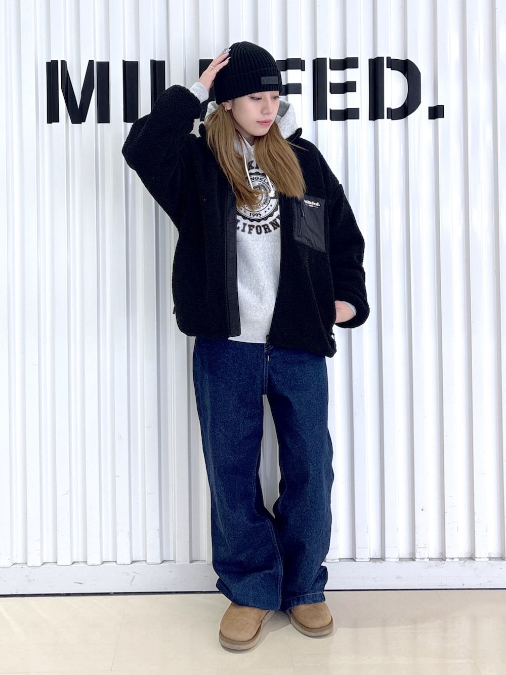 ブラック系のブルゾン、ブルー系のデニムパンツ、グレー系のパーカーを着用したレディースの冬コーディネートの3枚目の写真