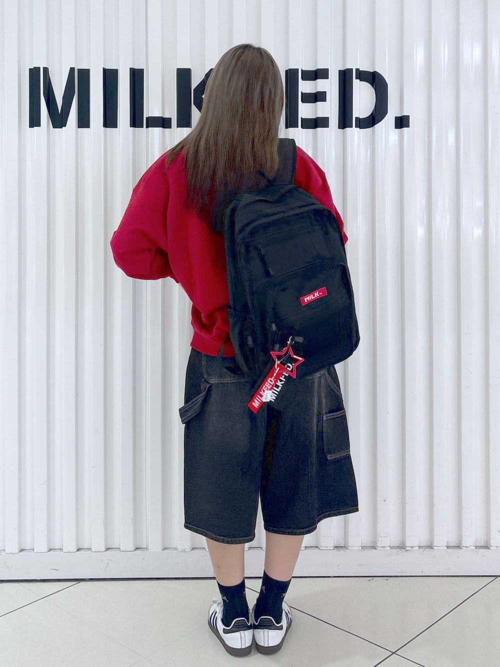 レッド系のスウェット、ホワイト系のデニムパンツ、レッド系のバックパック/リュックを着用したレディースの秋コーディネートの2枚目の写真