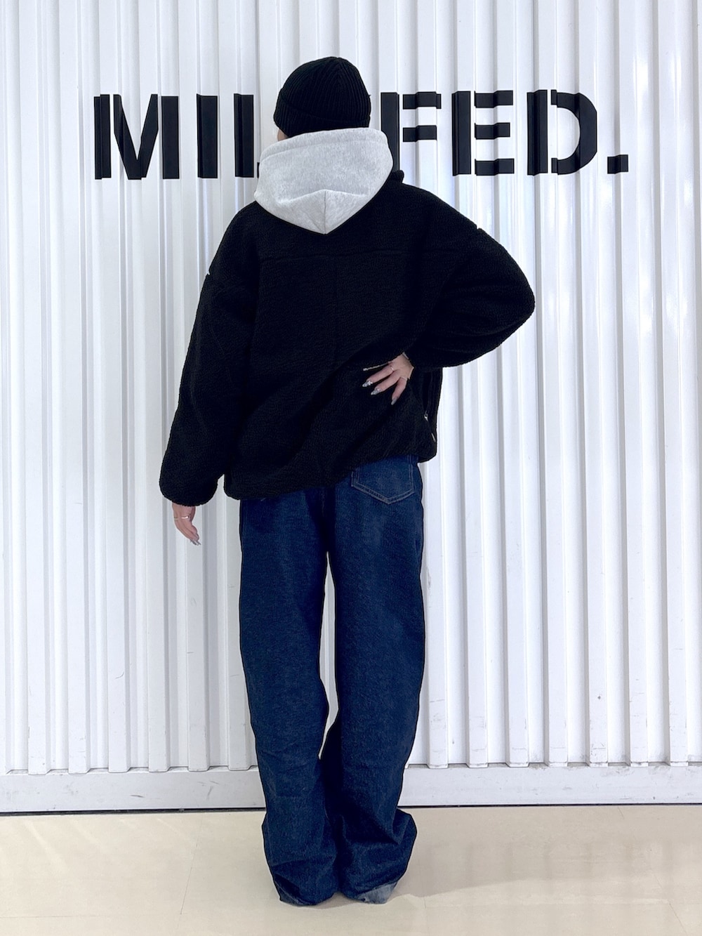 ブラック系のブルゾン、ブルー系のデニムパンツ、グレー系のパーカーを着用したレディースの冬コーディネートの4枚目の写真