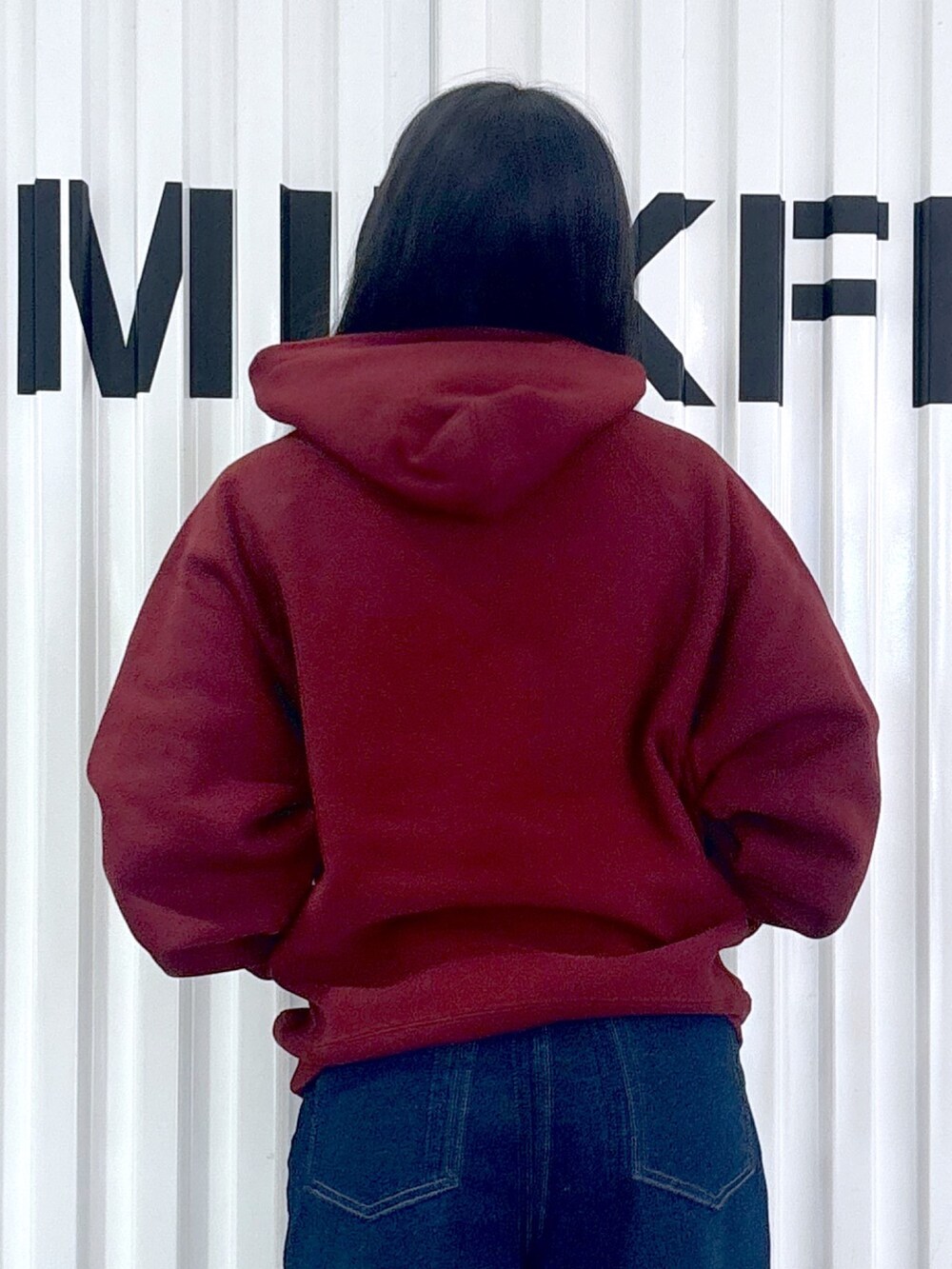 レッド系のパーカー、ブルー系のデニムパンツ、ブルー系のキャップを着用したレディースの秋コーディネートの4枚目の写真