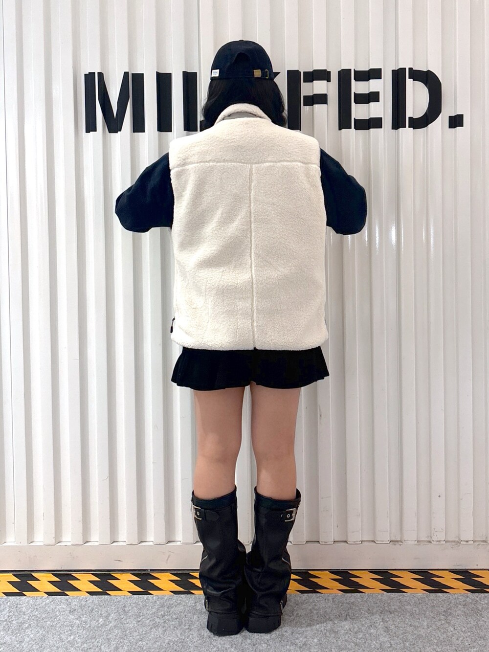 レッド系のスウェット、ホワイト系のベスト、ブラック系のその他パンツを着用したレディースの秋コーディネートの2枚目の写真