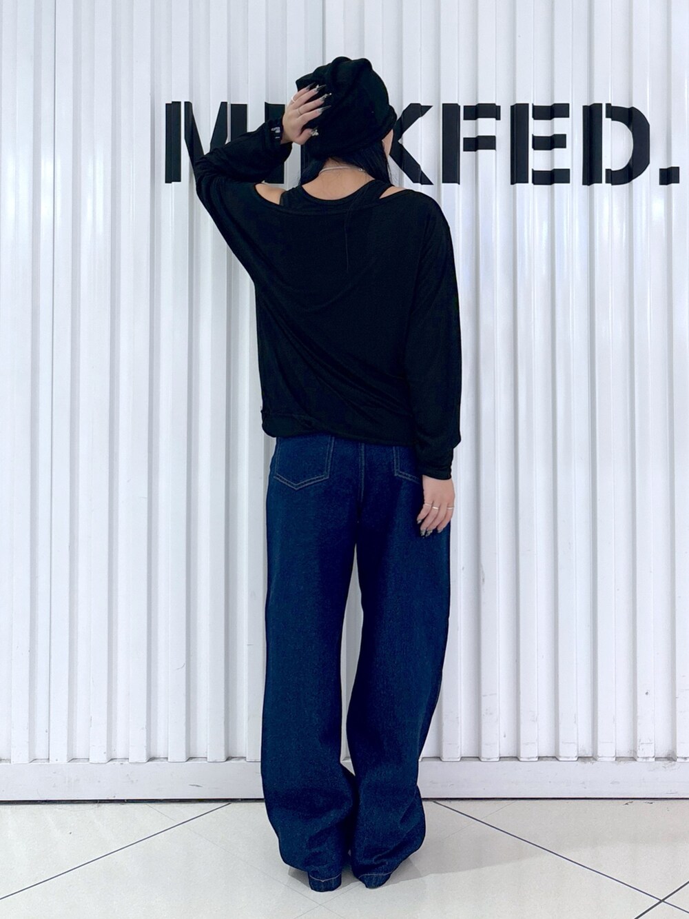 ブルー系のデニムパンツ、ブラック系のTシャツ/カットソー、ブラック系のニットキャップ/ビーニーを着用したレディースの秋コーディネートの6枚目の写真