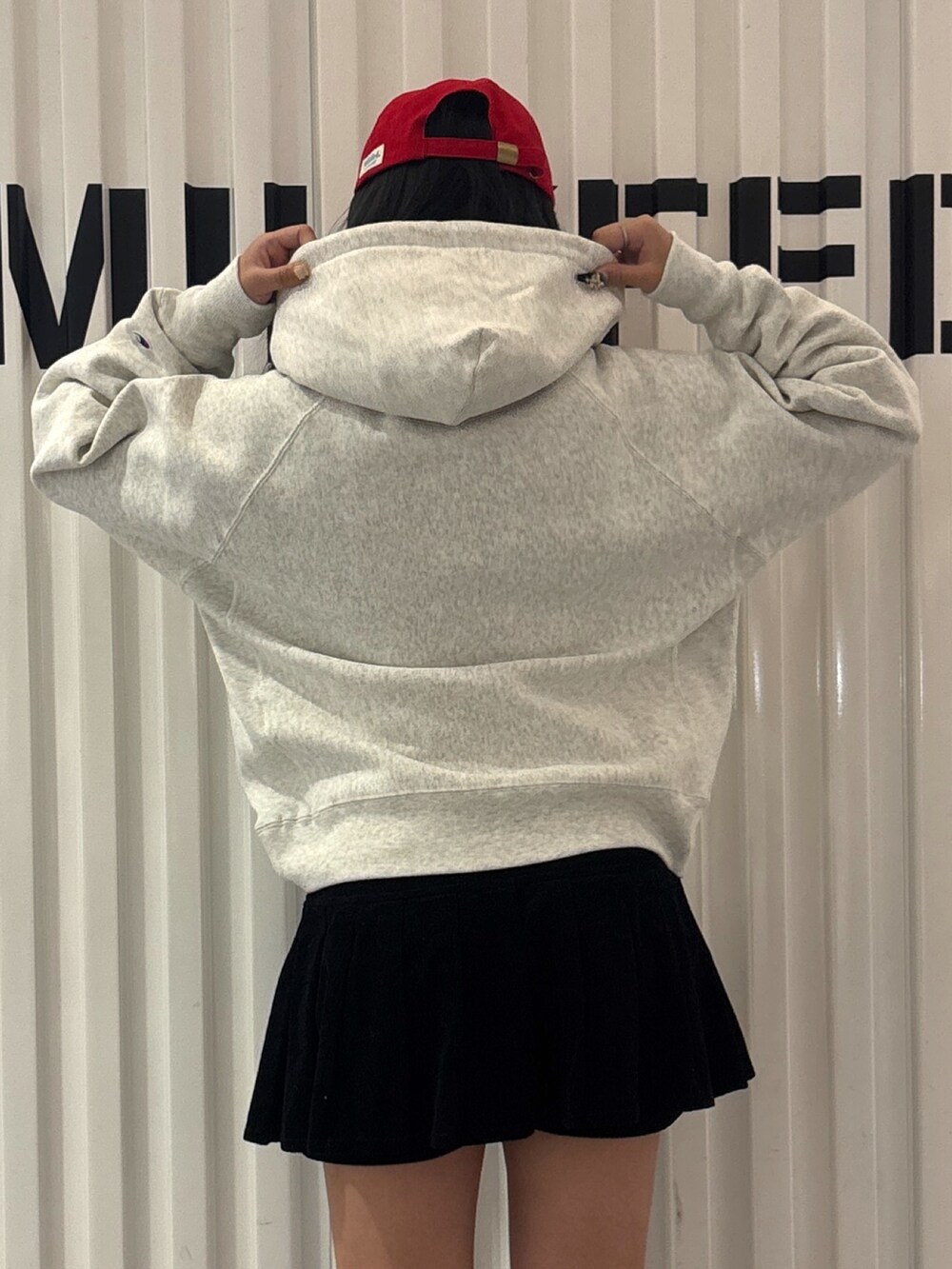 レッド系のパーカー、ブラック系のその他パンツ、ブルー系のキャップを着用したレディースの秋コーディネートの4枚目の写真