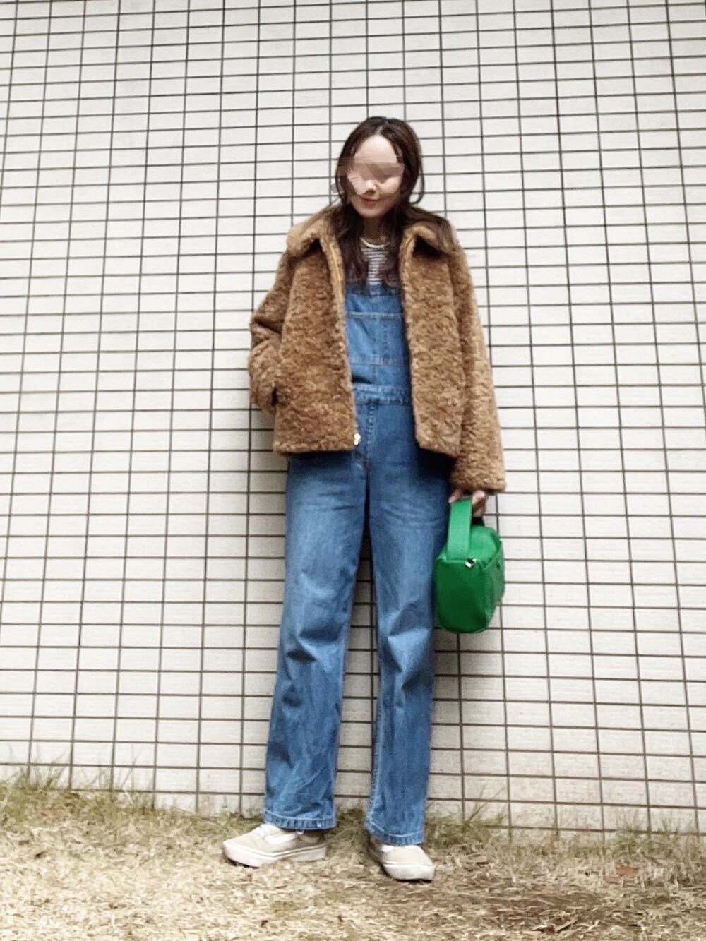 グリーン系のショルダーバッグ、ベージュ系のブルゾン、ブルー系のオールインワン・サロペットを着用したレディースの冬コーディネートの2枚目の写真