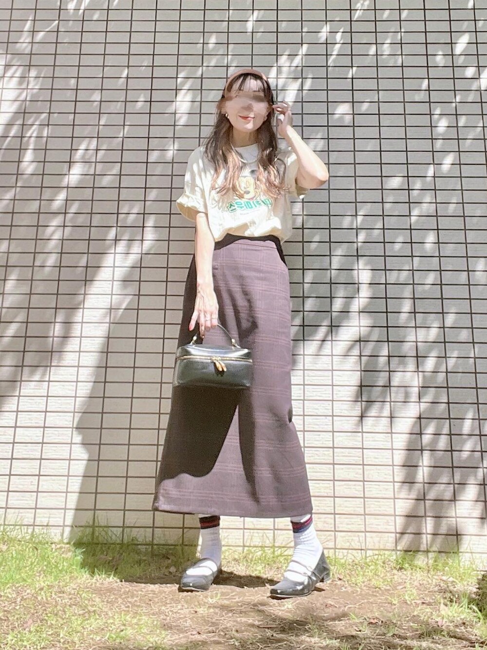 ホワイト系のTシャツ/カットソー、ブラウン系のスカート、ブラック系のバッグを着用したレディースの秋コーディネートの2枚目の写真