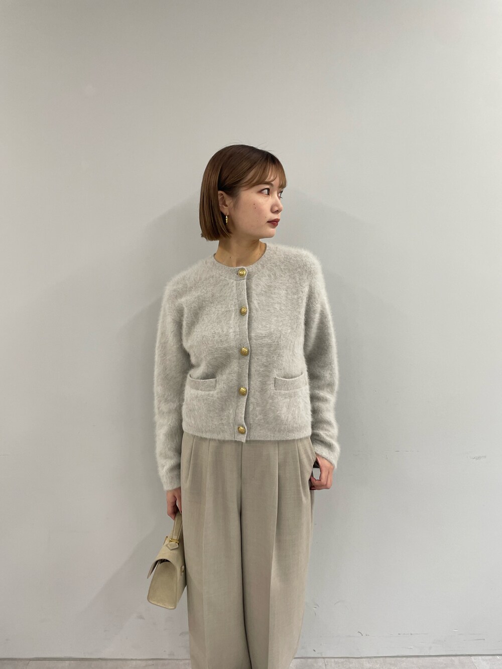 ベージュ系のカーディガン/ボレロ、ベージュ系のスラックス、ベージュ系のハンドバッグを着用したレディースの秋コーディネートの2枚目の写真