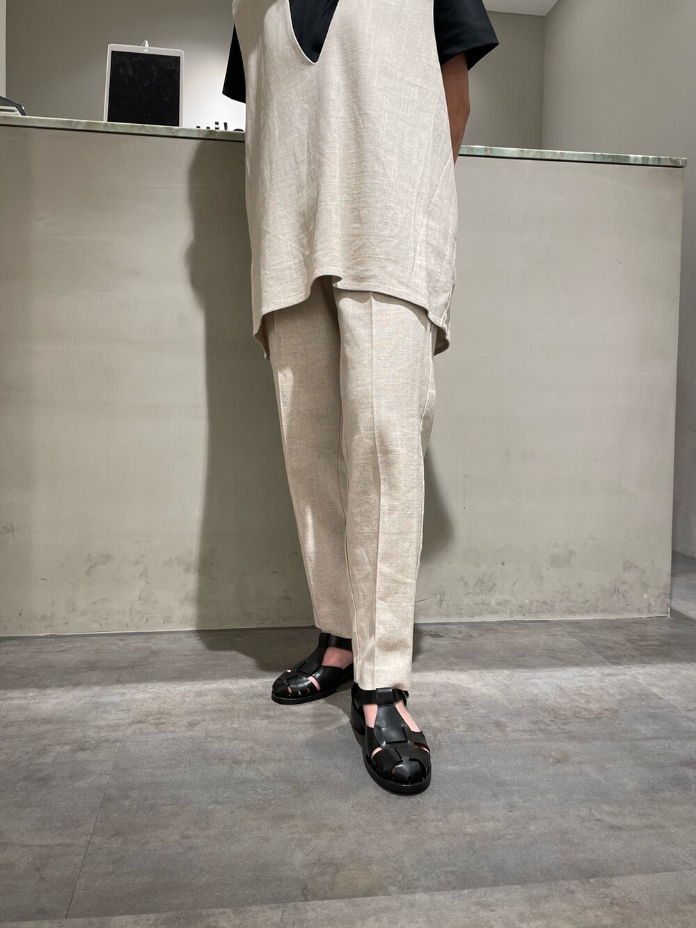 ホワイト系のベスト、ホワイト系のスラックス、ブラック系のサンダルを着用したレディースの春コーディネートの2枚目の写真