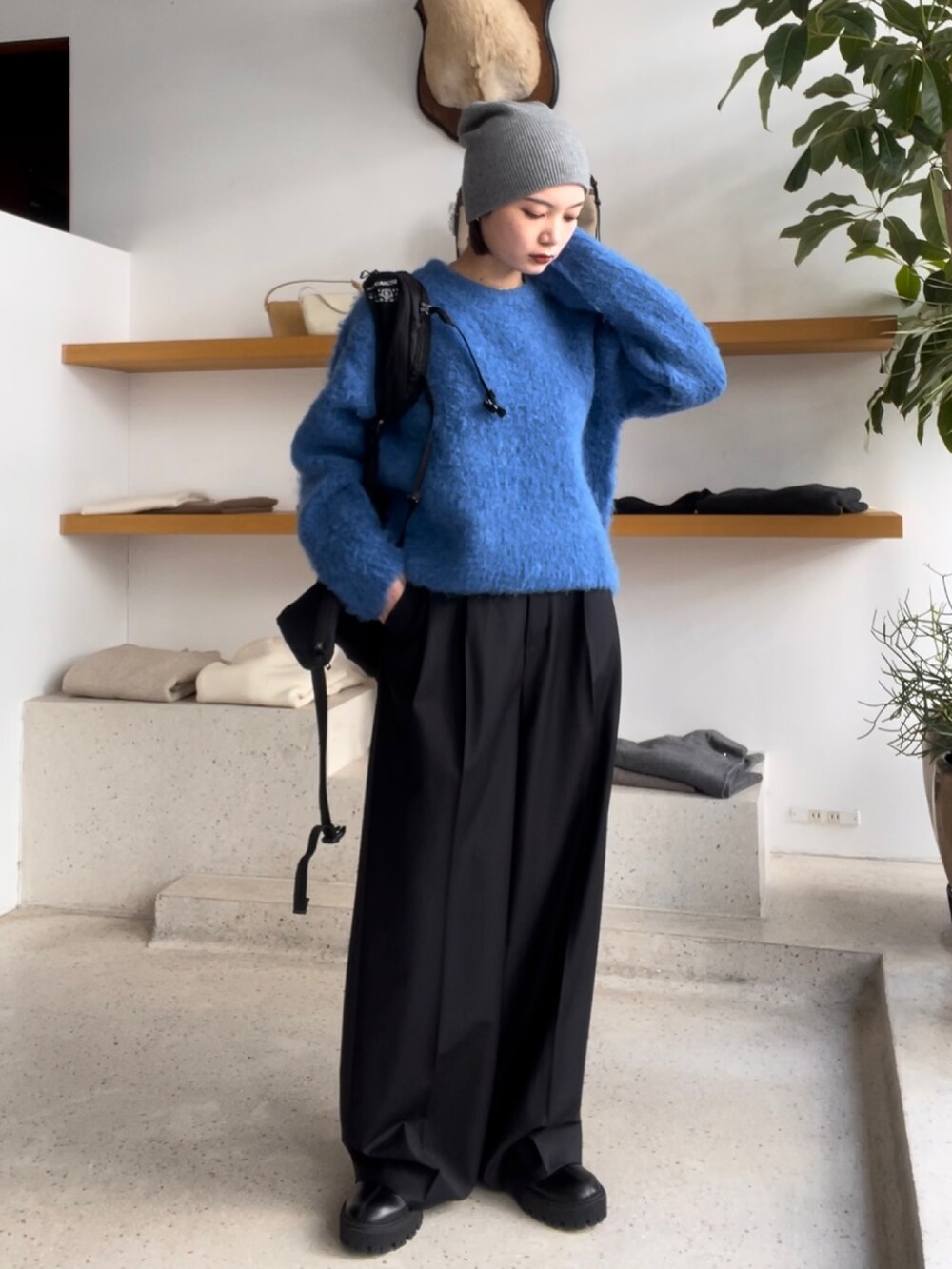 ブルー系のニット/セーター、グレー系のパンツ、ブラック系のブーツを着用したレディースの秋コーディネートの2枚目の写真