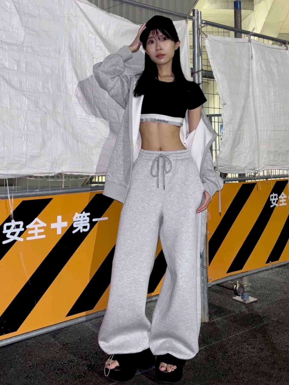 グレー系のパーカー、グレー系のスウェットパンツ、ブラック系のサンダルを着用したレディースの秋コーディネートの2枚目の写真