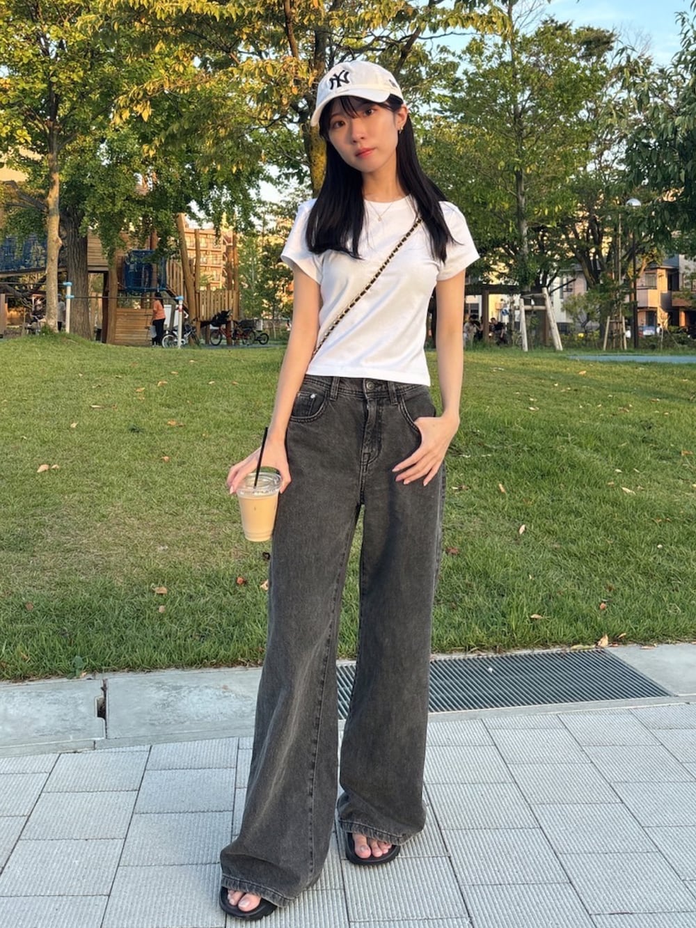 ホワイト系のTシャツ/カットソー、ブラック系のデニムパンツ、ブラック系のビーチサンダルを着用したレディースの夏コーディネートの2枚目の写真