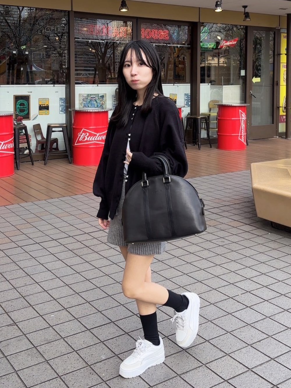 ブラック系のバッグ、ブラック系のカーディガン/ボレロ、ホワイト系のスニーカーを着用したレディースの春コーディネートの2枚目の写真