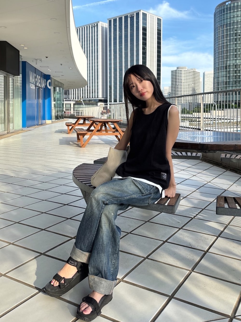 ブラック系のタンクトップ、ホワイト系のタンクトップ、ブルー系のデニムパンツを着用したレディースの夏コーディネートの2枚目の写真