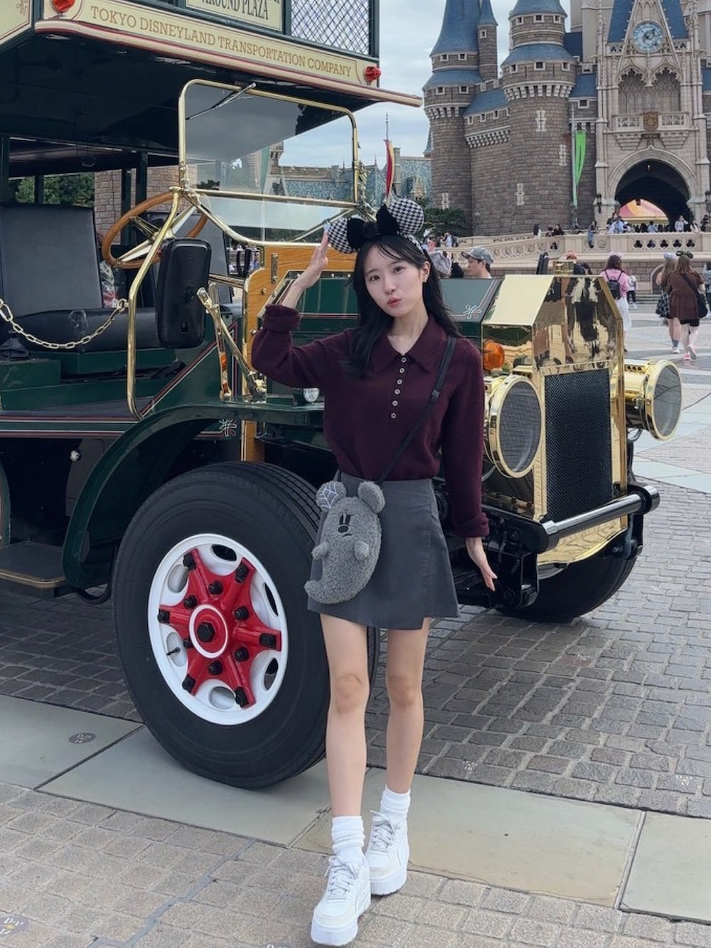 レッド系のニット/セーター、グレー系のスカート、ホワイト系のスニーカーを着用したレディースの秋コーディネートの2枚目の写真