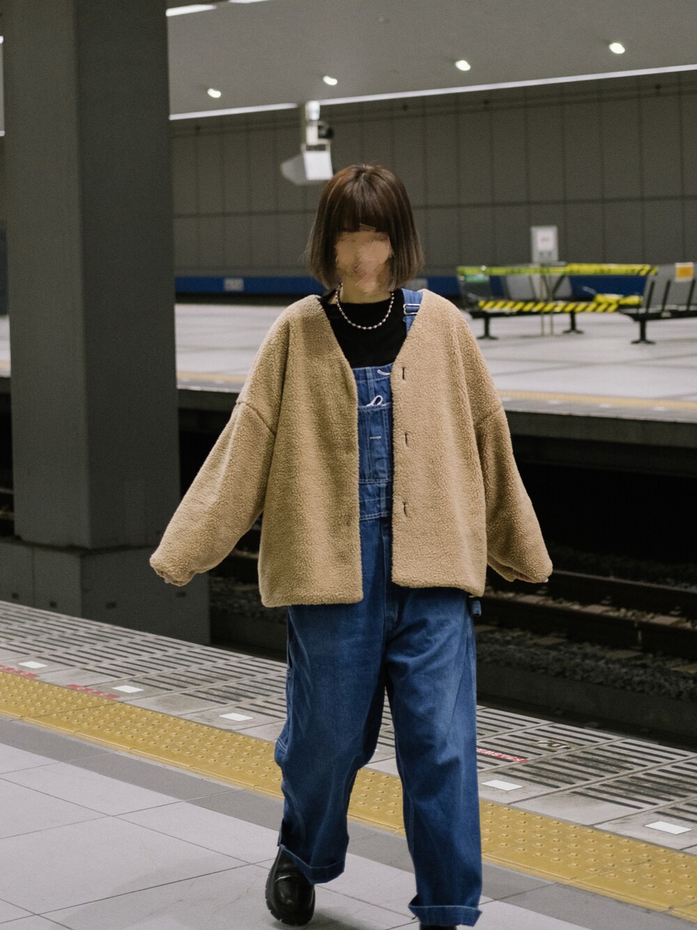 ブラウン系のジャケット/アウター、ブルー系のオールインワン・サロペット、ブラック系のブーツを着用したレディースの冬コーディネートの2枚目の写真