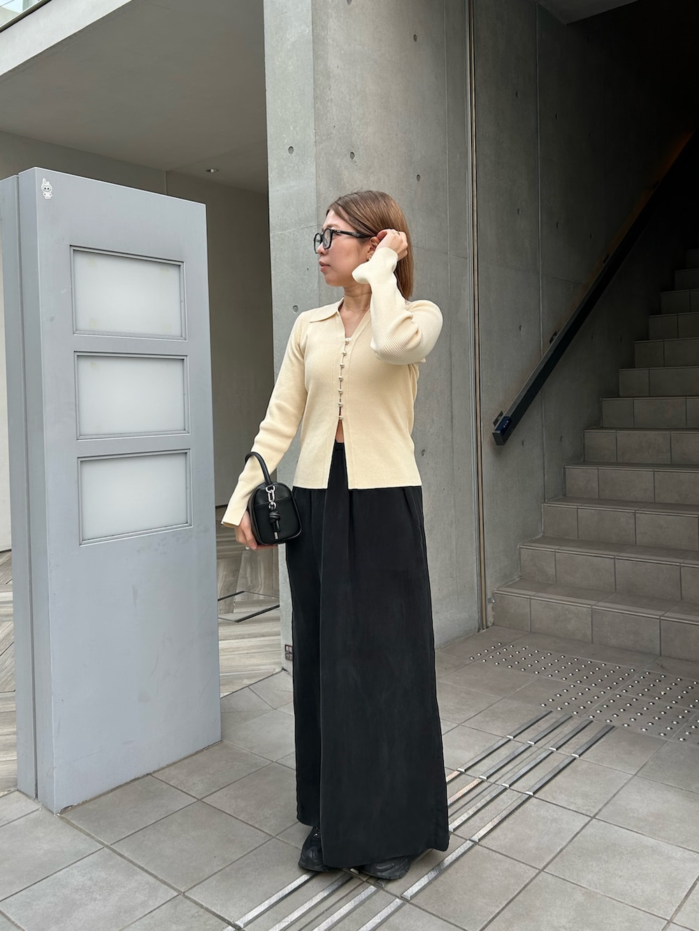 ホワイト系のカーディガン/ボレロ、ブラック系のハンドバッグ、ブラック系のスカートを着用したレディースの冬コーディネートの2枚目の写真