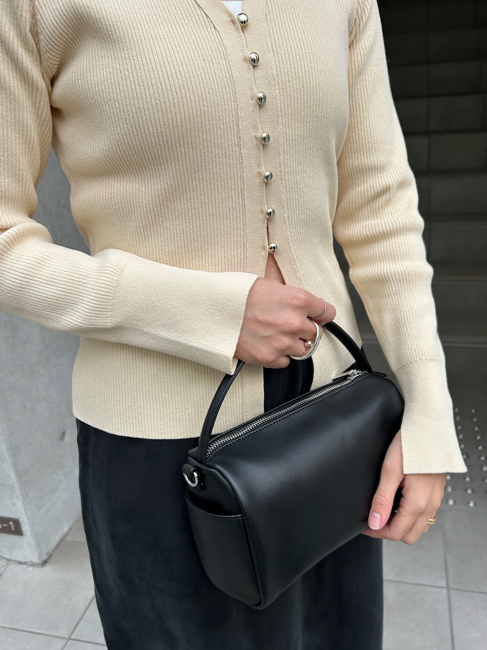 ホワイト系のカーディガン/ボレロ、ブラック系のハンドバッグ、ブラック系のスカートを着用したレディースの冬コーディネートの5枚目の写真