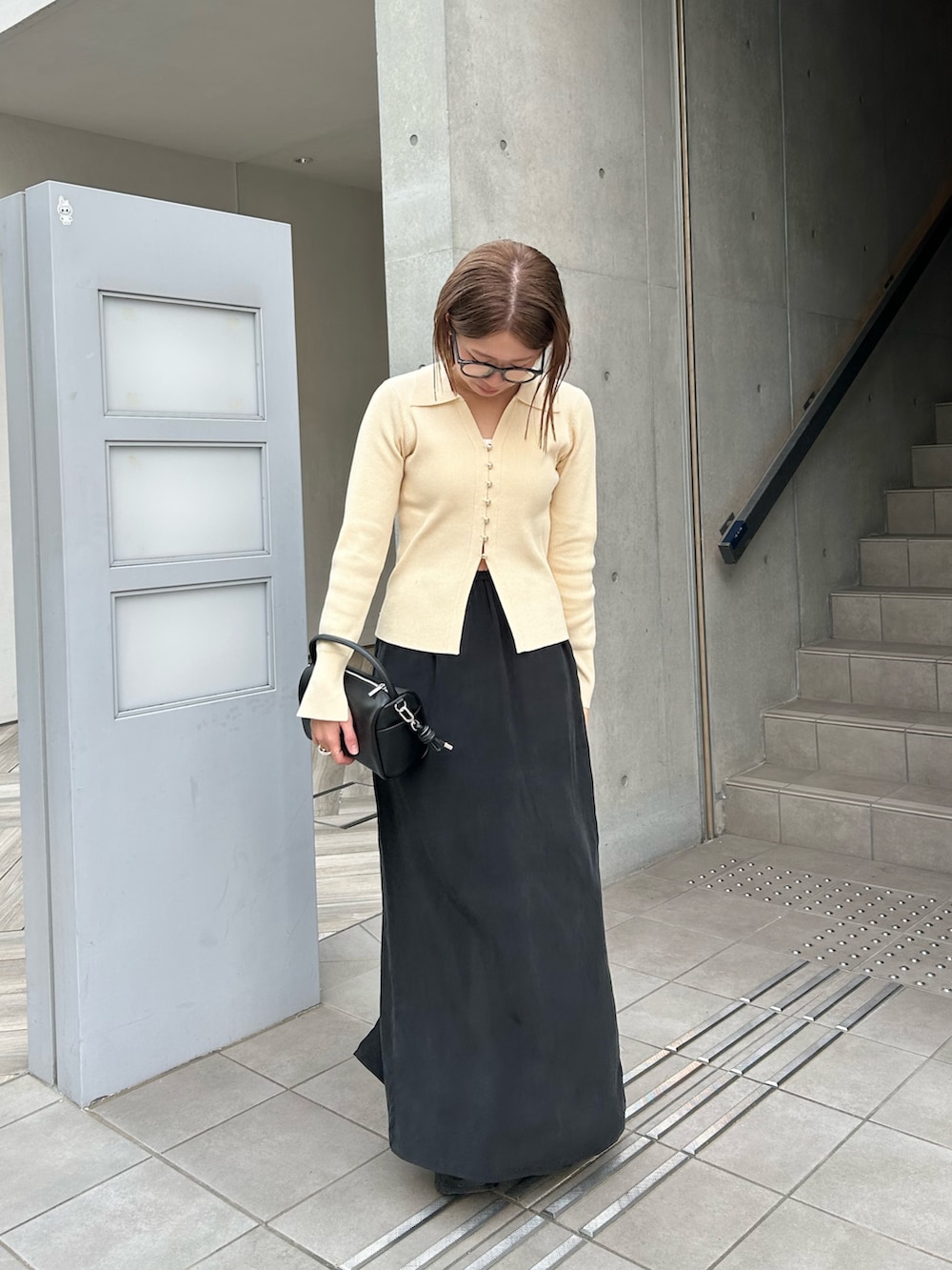 ホワイト系のカーディガン/ボレロ、ブラック系のハンドバッグ、ブラック系のスカートを着用したレディースの冬コーディネートの4枚目の写真