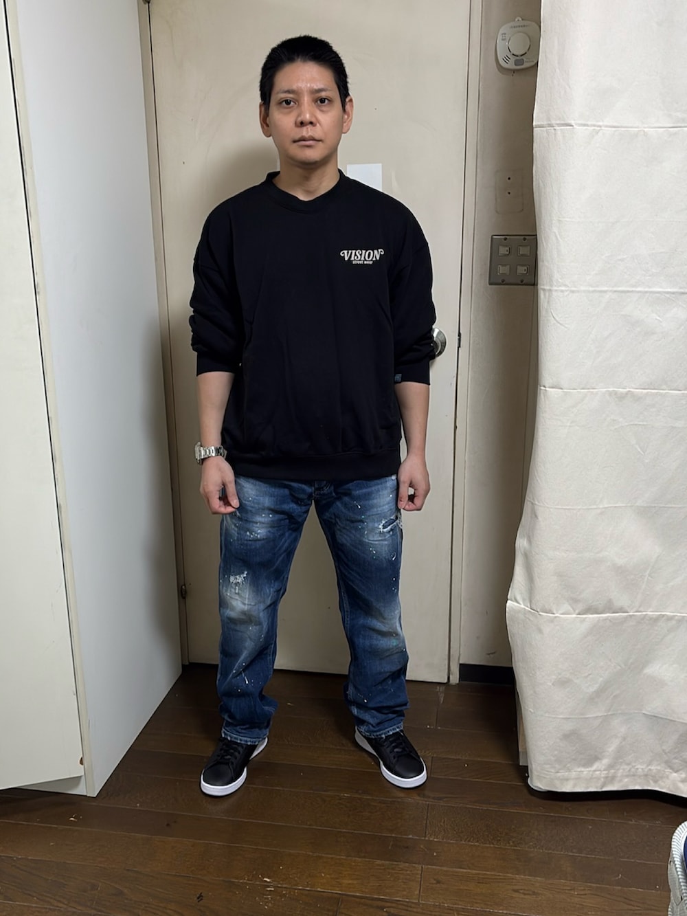 ブルー系のデニムパンツ、ブラック系のスウェット、ブラック系のスニーカーを着用したメンズの秋コーディネートの2枚目の写真