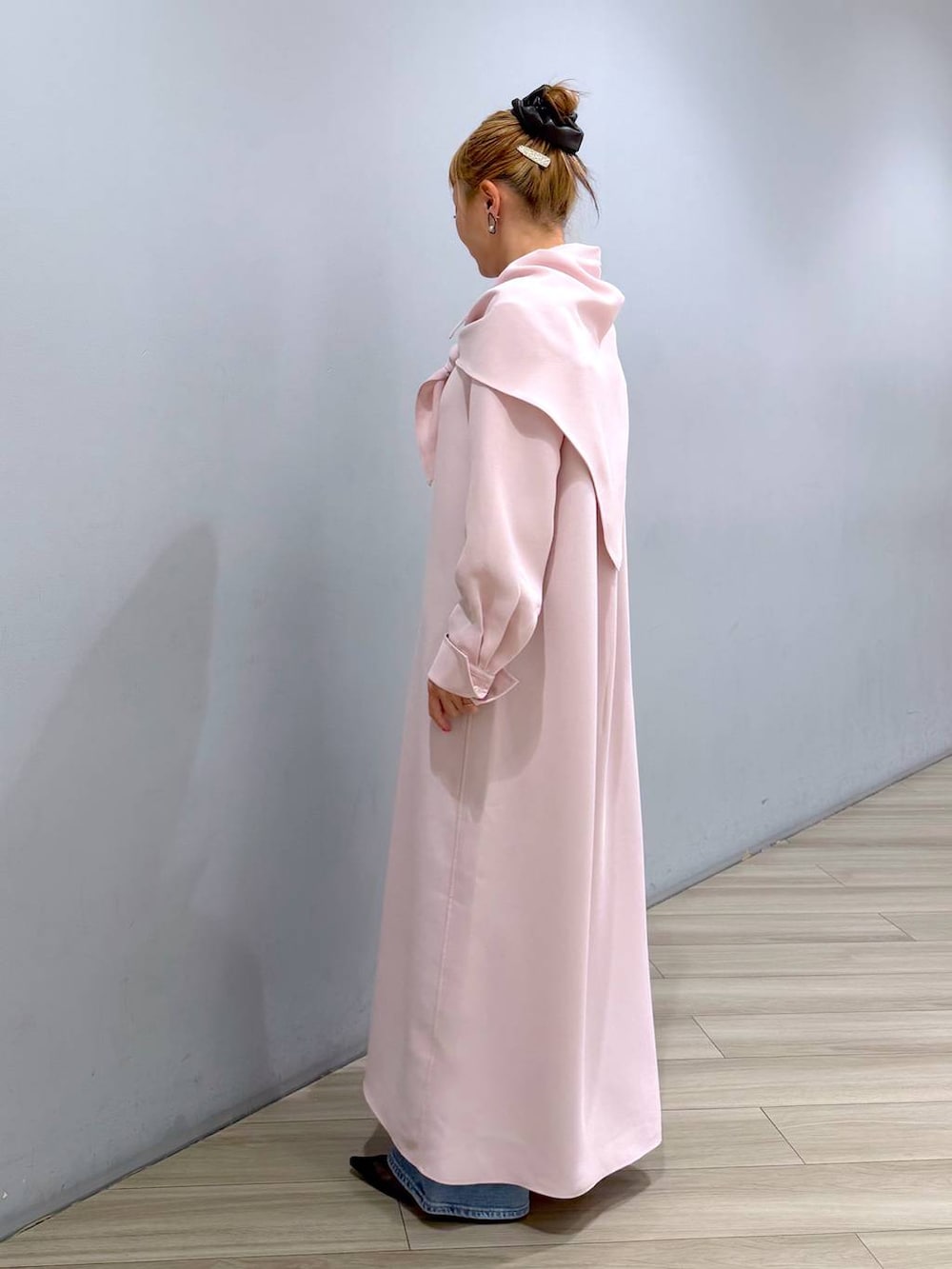 ピンク系のシャツワンピース、ブルー系のデニムパンツ、ホワイト系のハンドバッグを着用したレディースの冬コーディネートの3枚目の写真