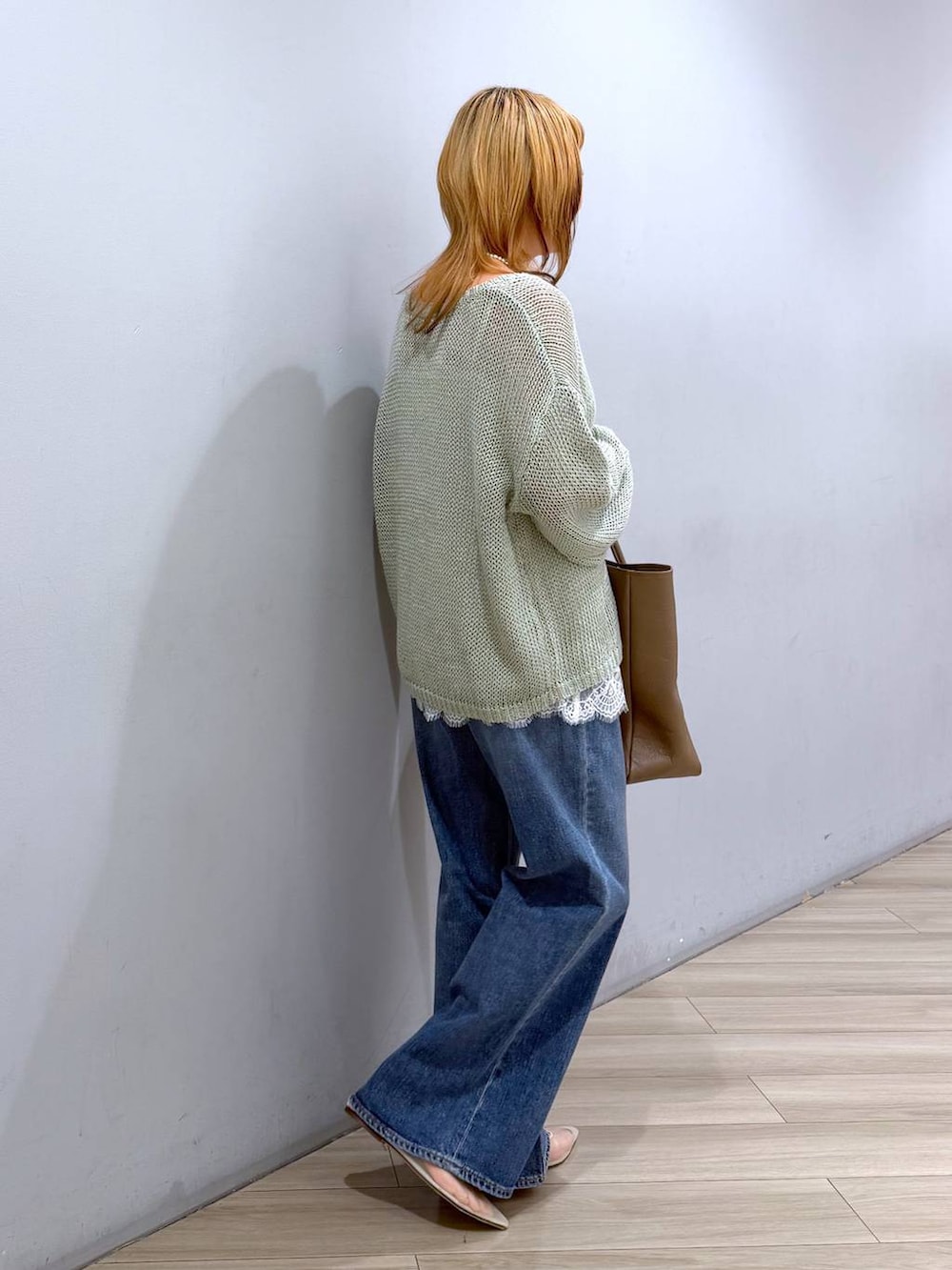 ベージュ系のパンプス、ブルー系のデニムパンツ、ホワイト系のキャミソールを着用したレディースの春コーディネートの4枚目の写真