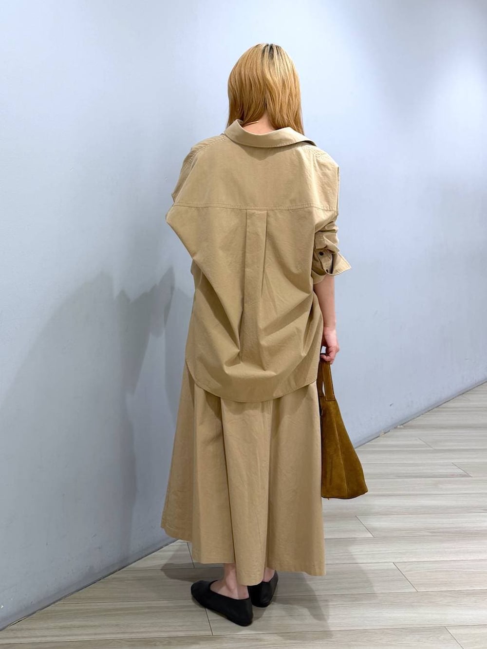 ブラウン系のハンドバッグ、ブラック系のパンプス、ベージュ系のスカートを着用したレディースの春コーディネートの2枚目の写真