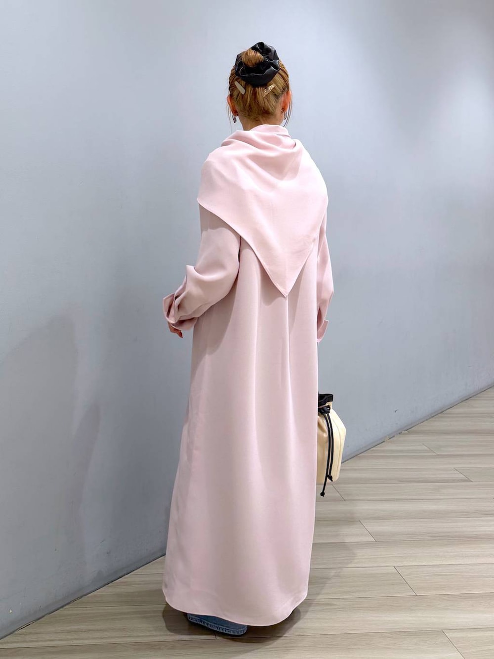 ピンク系のシャツワンピース、ブルー系のデニムパンツ、ホワイト系のハンドバッグを着用したレディースの冬コーディネートの2枚目の写真