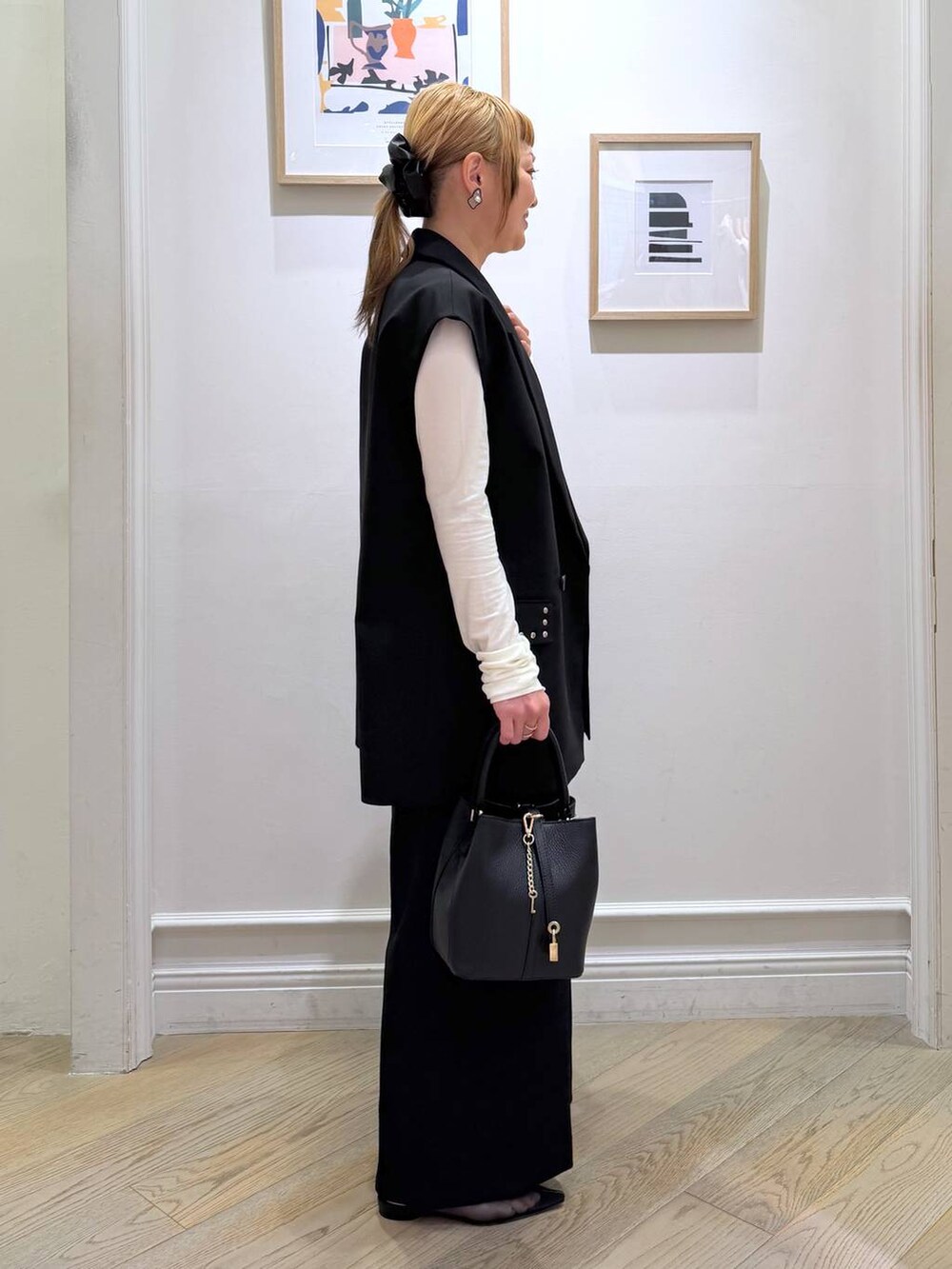 ブラック系のベスト、ブラック系のスラックス、ホワイト系のTシャツ/カットソーを着用したレディースの冬コーディネートの2枚目の写真