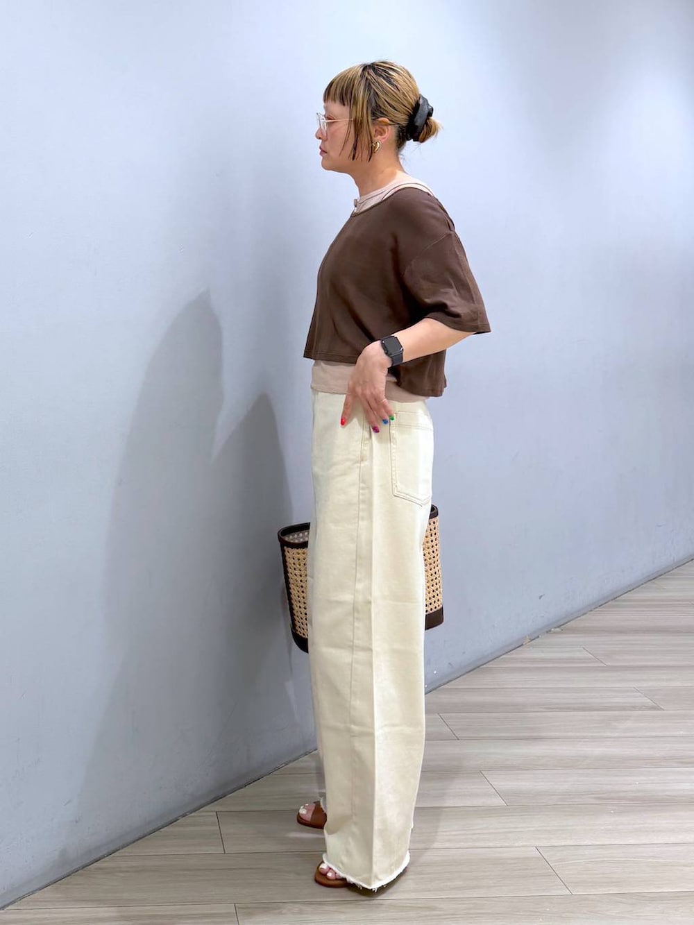ベージュ系のデニムパンツ、ブラウン系のアンサンブル、ベージュ系のかごバッグを着用したレディースの春コーディネートの2枚目の写真