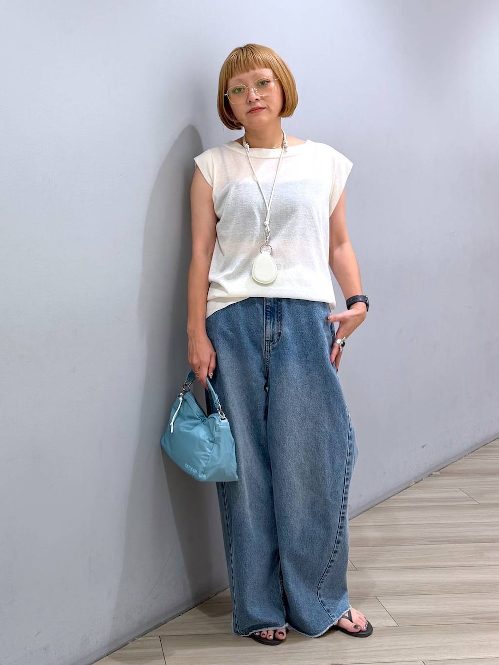 ブルー系のデニムパンツ、ホワイト系のTシャツ/カットソー、ブルー系のハンドバッグを着用したレディースの夏コーディネートの5枚目の写真