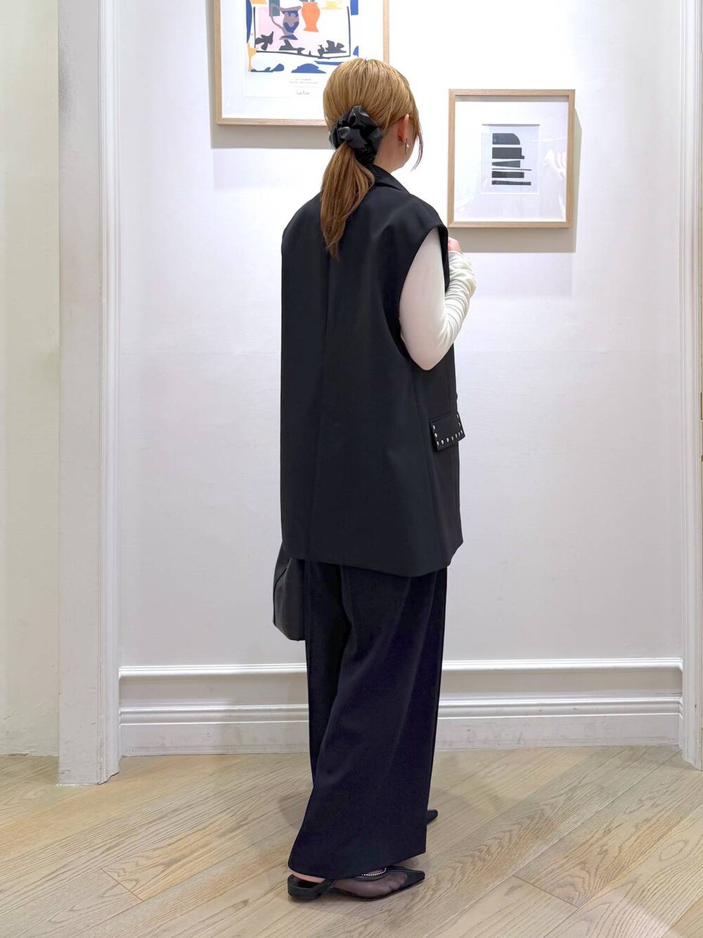 ブラック系のベスト、ブラック系のスラックス、ホワイト系のTシャツ/カットソーを着用したレディースの冬コーディネートの3枚目の写真