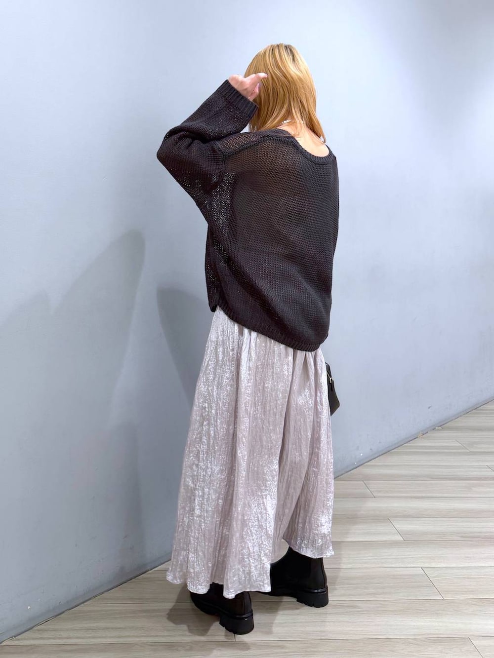 ブラック系のブーツ、ブラック系のボストンバッグ、シルバー系のスカートを着用したレディースの春コーディネートの3枚目の写真