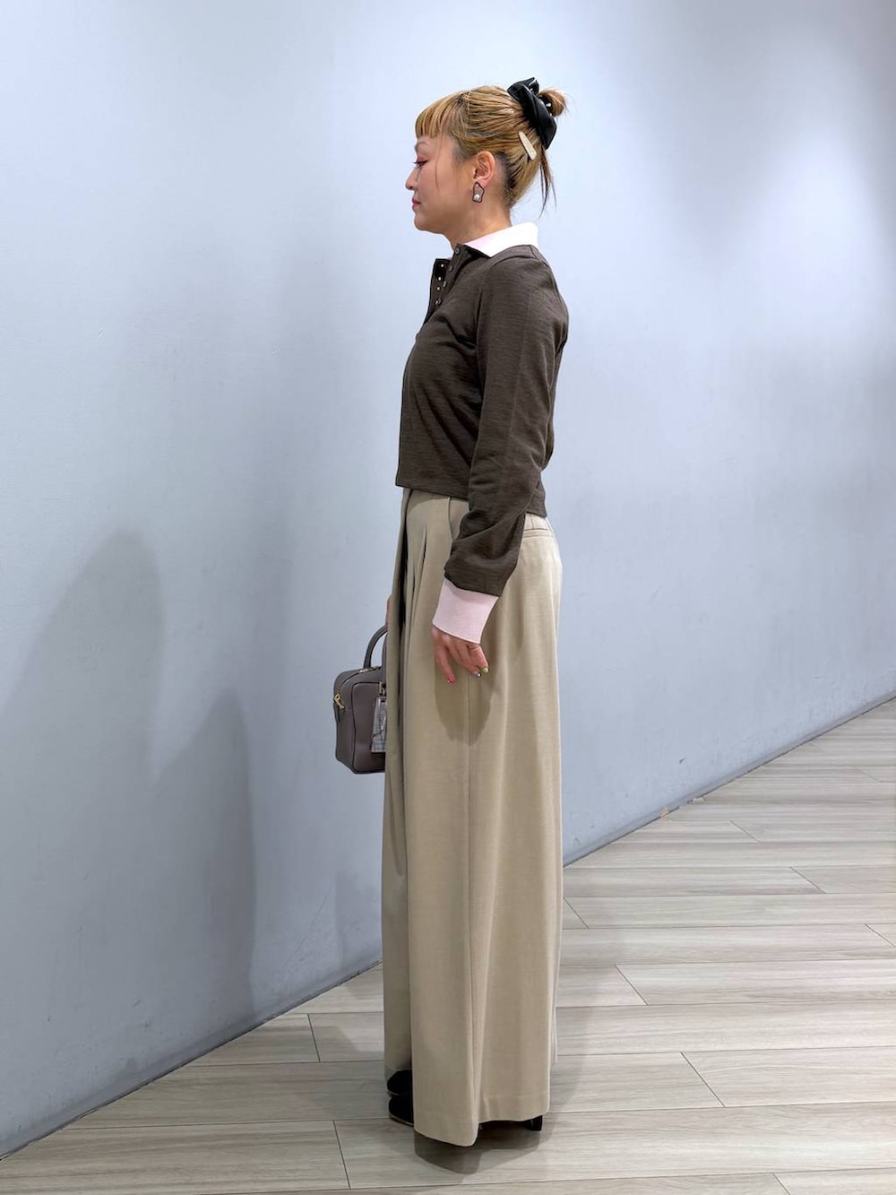 ベージュ系のボストンバッグ、ベージュ系のその他パンツ、ブラウン系のポロシャツを着用したレディースの冬コーディネートの3枚目の写真