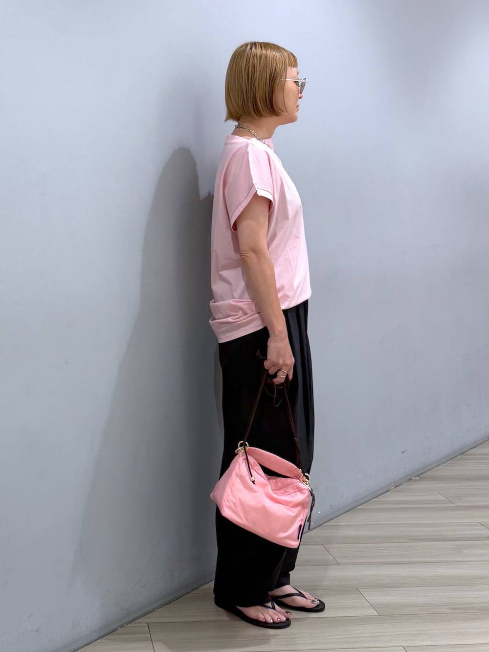 ピンク系のTシャツ/カットソー、ピンク系のハンドバッグ、ブラック系のその他パンツを着用したレディースの夏コーディネートの2枚目の写真