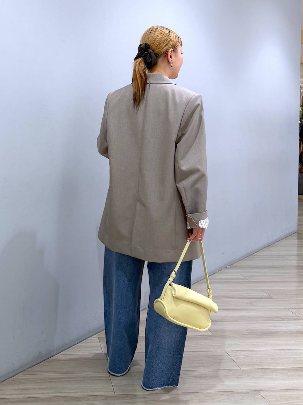 ブルー系のデニムパンツ、イエロー系のハンドバッグ、ホワイト系のTシャツ/カットソーを着用したレディースの春コーディネートの4枚目の写真