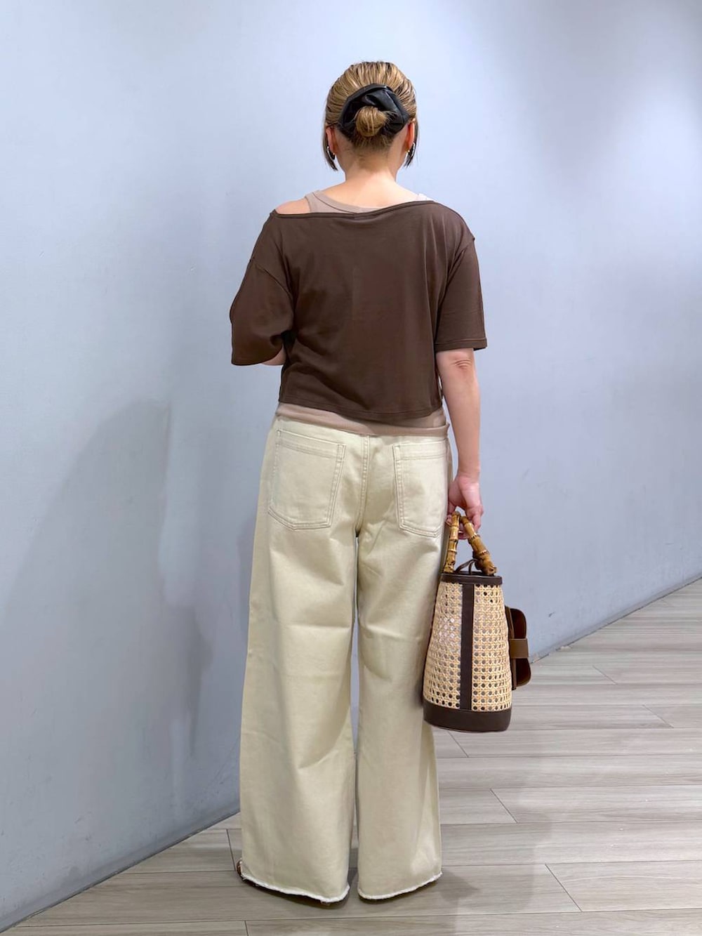 ベージュ系のデニムパンツ、ブラウン系のアンサンブル、ベージュ系のかごバッグを着用したレディースの春コーディネートの3枚目の写真