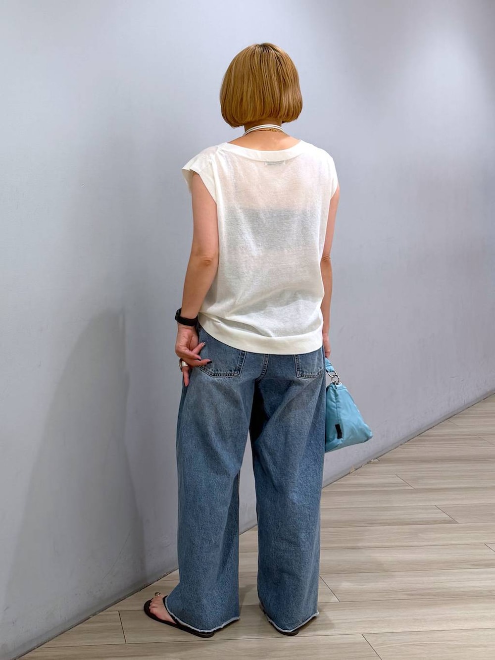 ブルー系のデニムパンツ、ホワイト系のTシャツ/カットソー、ブルー系のハンドバッグを着用したレディースの夏コーディネートの4枚目の写真