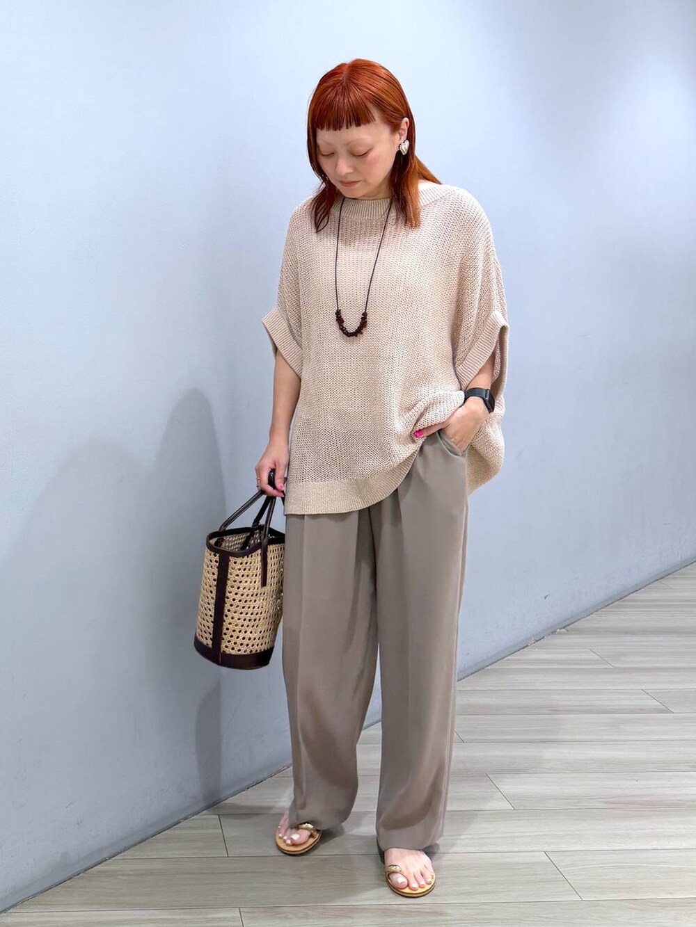 ベージュ系のニット/セーター、ベージュ系のかごバッグ、ベージュ系のスラックスを着用したレディースの夏コーディネートの4枚目の写真