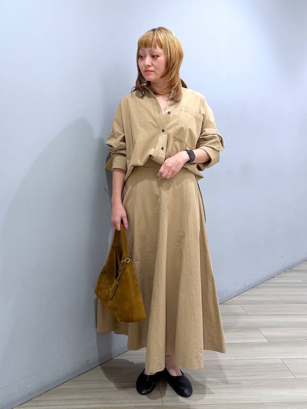 ブラウン系のハンドバッグ、ブラック系のパンプス、ベージュ系のスカートを着用したレディースの春コーディネートの3枚目の写真