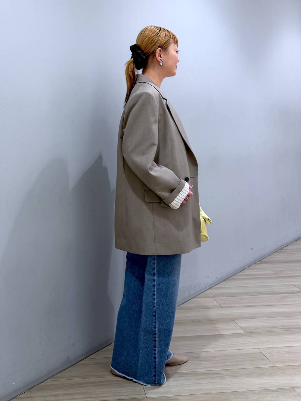 ブルー系のデニムパンツ、イエロー系のハンドバッグ、ホワイト系のTシャツ/カットソーを着用したレディースの春コーディネートの3枚目の写真