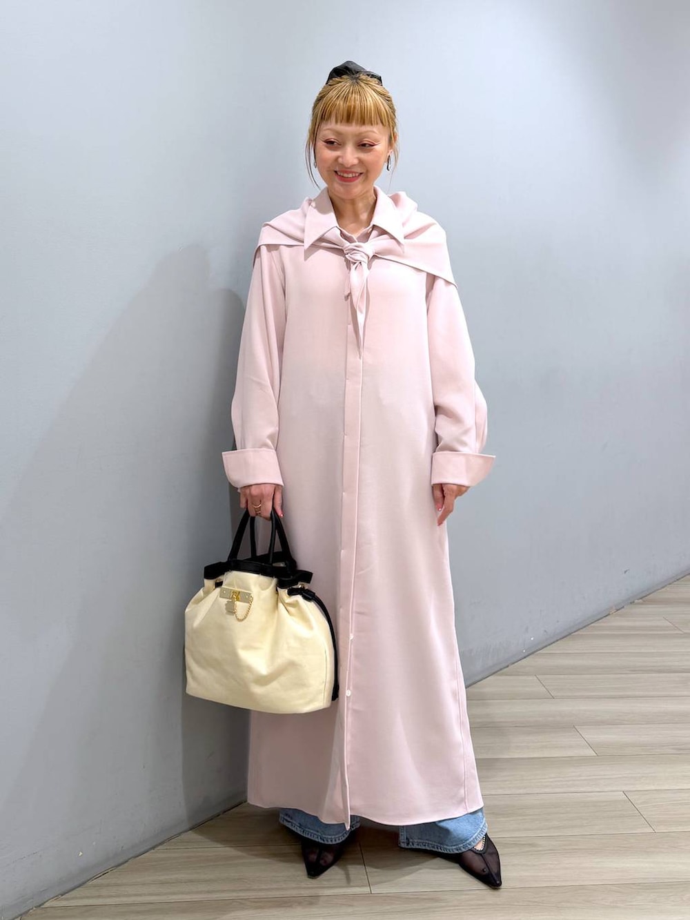 ピンク系のシャツワンピース、ブルー系のデニムパンツ、ホワイト系のハンドバッグを着用したレディースの冬コーディネートの6枚目の写真