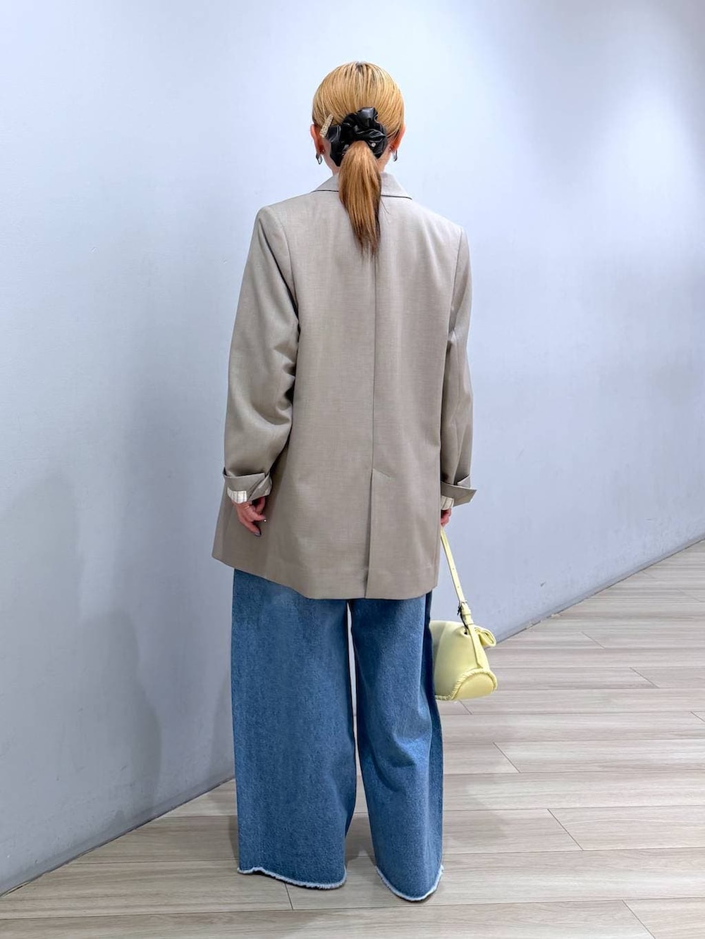 ブルー系のデニムパンツ、イエロー系のハンドバッグ、ホワイト系のTシャツ/カットソーを着用したレディースの春コーディネートの5枚目の写真